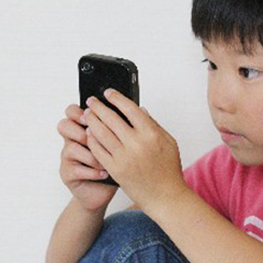 スマートフォンを操作する男の子の写真